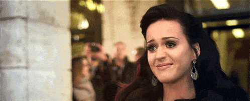 a woman with a sad look on her face is standing in front of a crowd