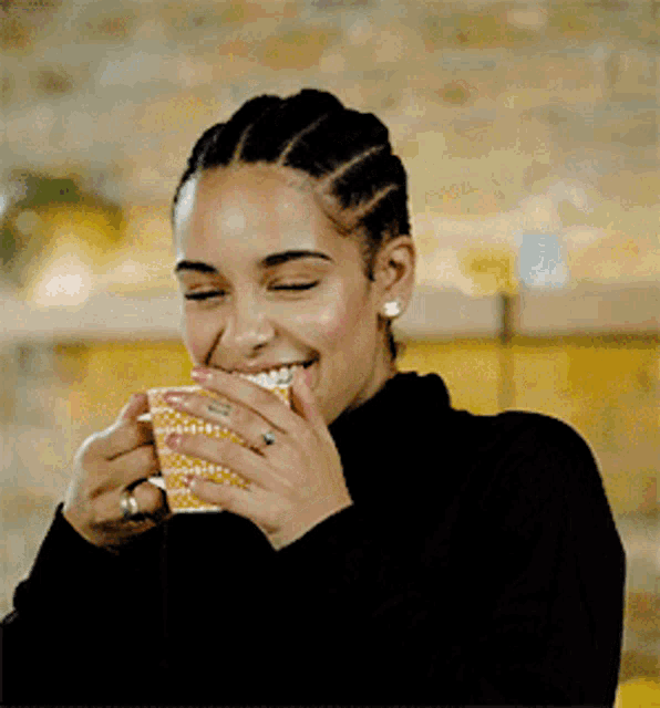 a woman is holding a cup of coffee and smiling .