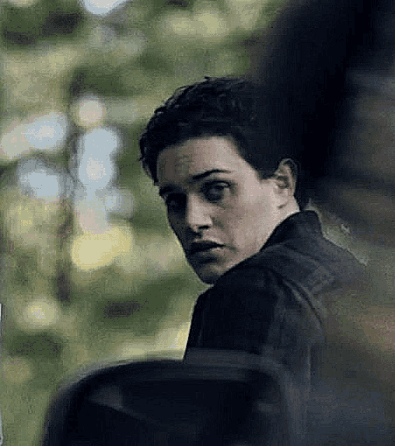 a young man in a black jacket is looking at the camera in a car .