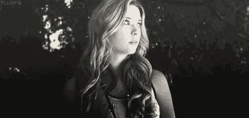 a black and white photo of a woman with long hair looking up at the sky .