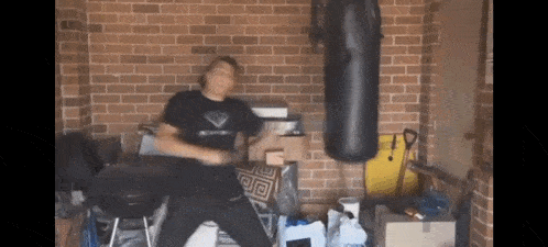 a man is standing in front of a punching bag in a messy room .