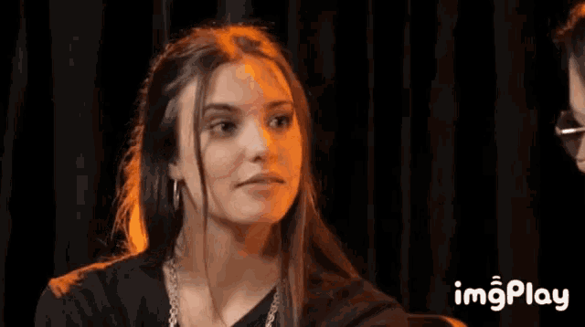 a woman with long hair is making a funny face while sitting in front of a man .