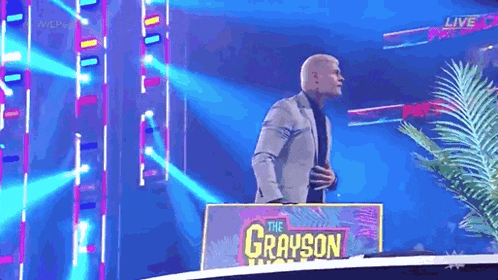 a man in a suit and tie is standing in front of a sign that says the grayson .
