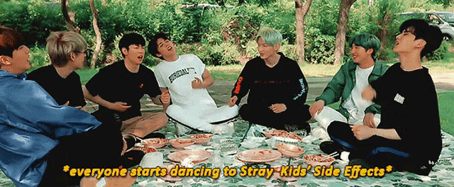 a group of young men are sitting on a blanket in a park with the words everyone starts dancing