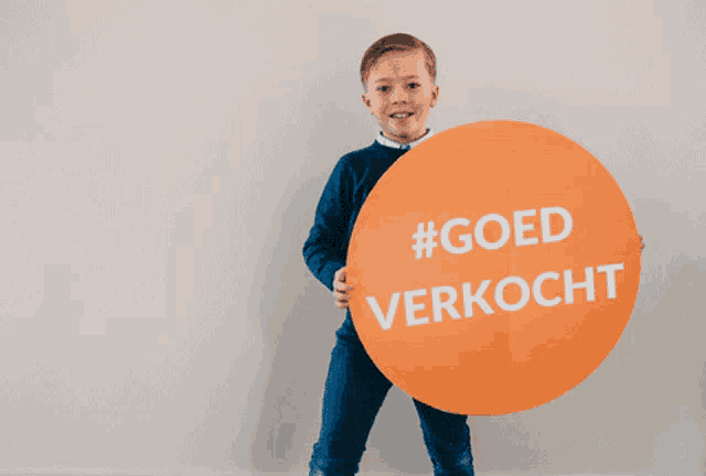 a young boy holds a sign that says #goed verkocht