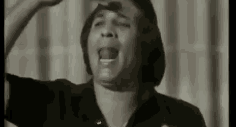 a man in a black shirt is screaming with his mouth open in a black and white photo .