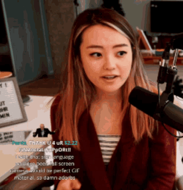 a woman sitting in front of a microphone with a sign that says " thank u 4 ur $ 22.22 "
