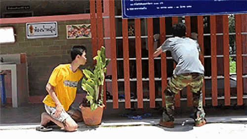a man wearing a yellow shirt that says ' thailand ' on it is kneeling down