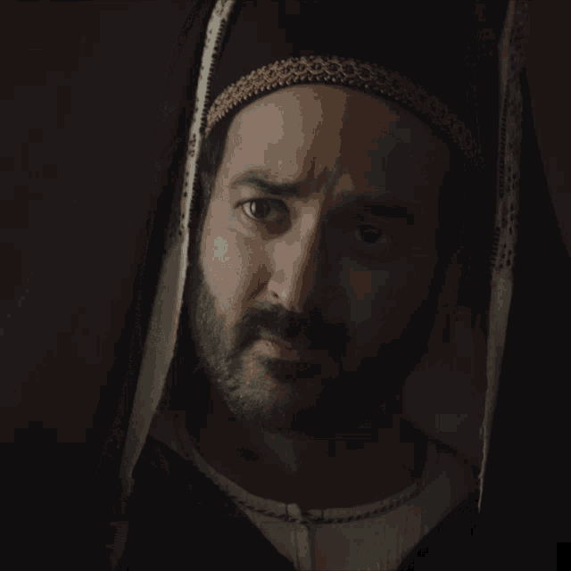 a man with a beard is wearing a black hat and a white shirt