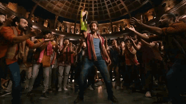 a man in a red shirt is holding a green object in front of a group of people