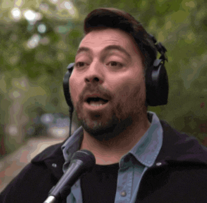 a man wearing headphones singing into a microphone with his mouth open