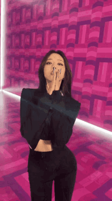 a woman is standing in front of a pink wall with the letter t on it