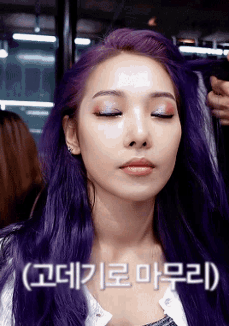 a woman with purple hair has her eyes closed and a foreign language written on her face