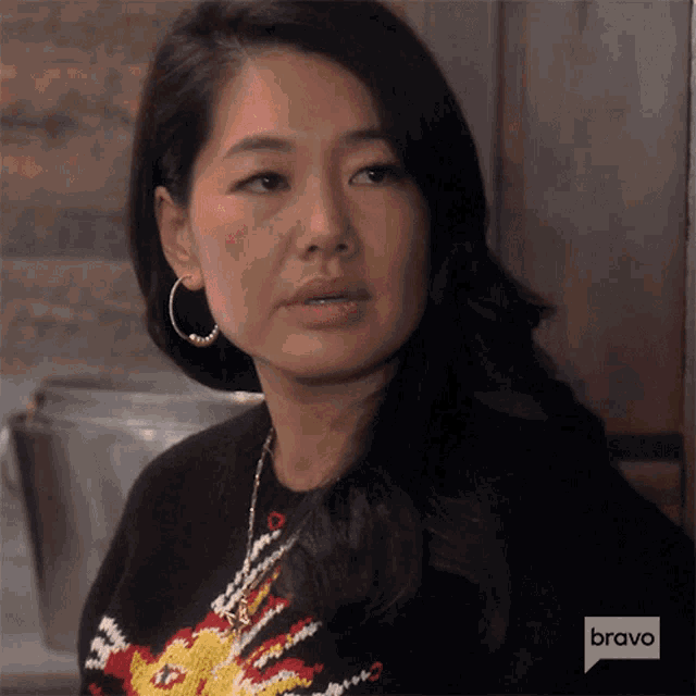 a woman wearing a black sweater and hoop earrings is on bravo television