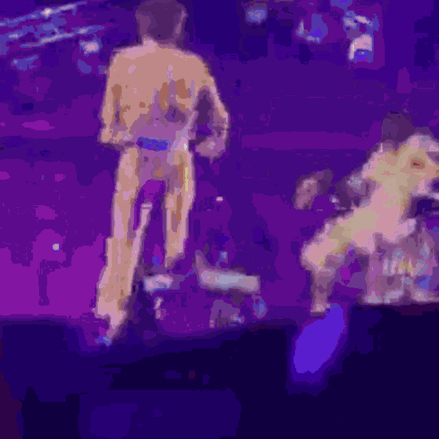 a blurry image of a man standing on a stage with a purple background