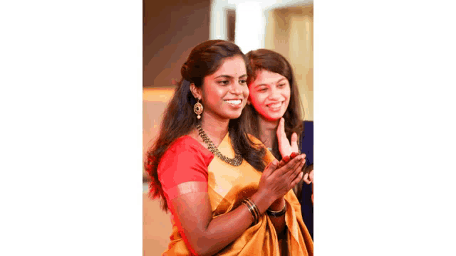 two women are posing for a picture and one is wearing a yellow sari