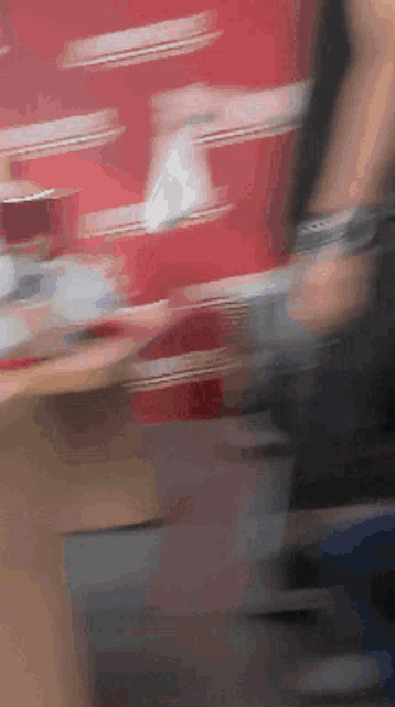 a blurry picture of a person walking in front of a red wall with the word coca cola on it