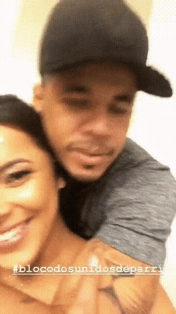 a man in a black hat is hugging a woman in a grey shirt ..