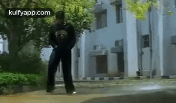 a man is standing on a sidewalk in front of a building while holding a gun .