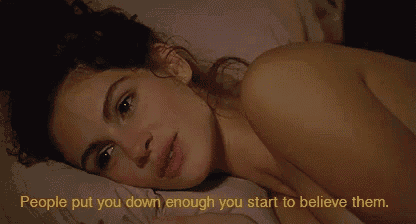 a naked woman is laying on a bed with the words " people put you down enough you start to believe them "