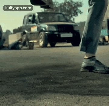 a person is standing on the ground in front of a car .