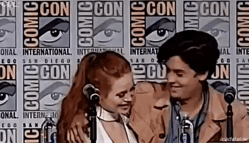 a man and a woman are hugging each other in front of a microphone .
