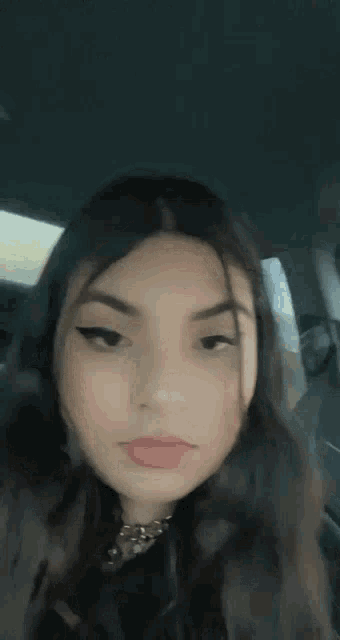 a girl is sticking her tongue out while sitting in a car .