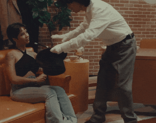 a woman sits on a couch talking to a man in a living room