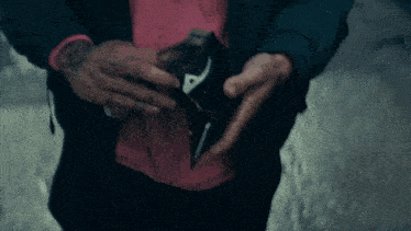 a man in a pink shirt is holding an empty wallet in his hands