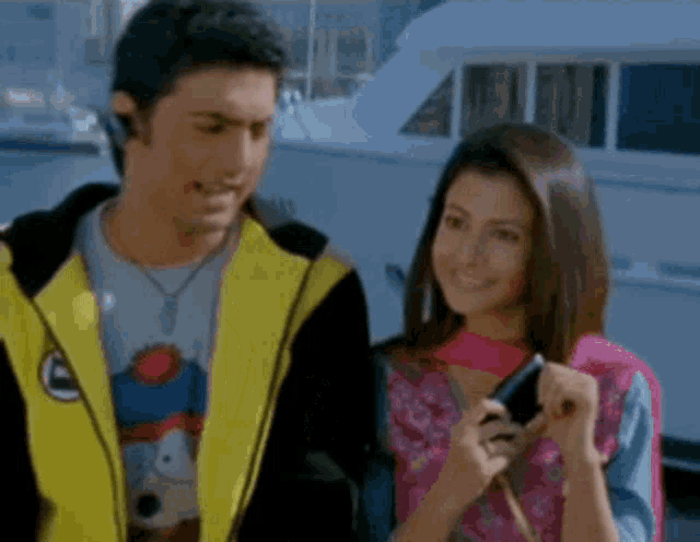 a man in a yellow jacket is standing next to a woman in a pink dress