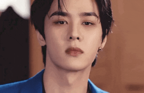 a close up of a man 's face wearing a blue suit and earrings .