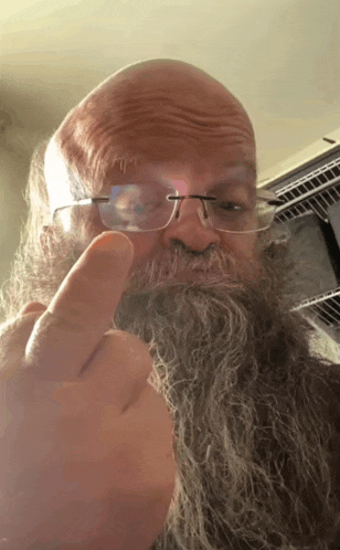 a bald man with a beard and glasses giving the middle finger