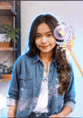 a woman in a denim shirt is holding a purple object in her hand .