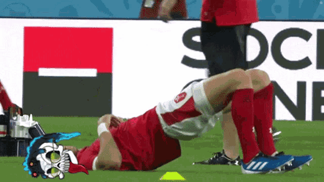 a soccer player is stretching on the field in front of a sign that says socce