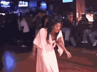 a woman in a white dress is dancing in a dark room