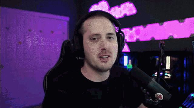 a man wearing headphones and a black shirt is talking into a microphone