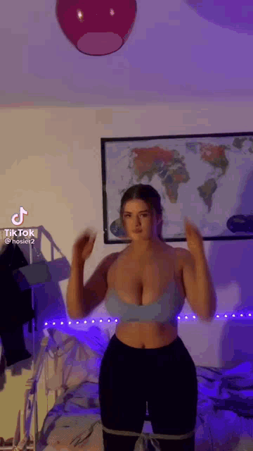 a woman in a blue bra and black pants is standing in a room with a map of the world on the wall .
