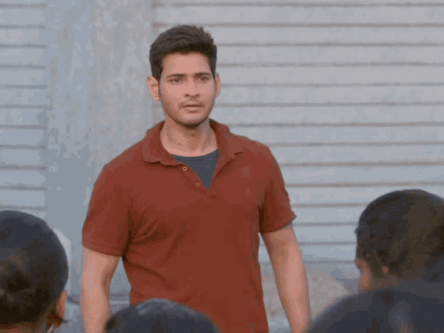 a man in a red polo shirt is standing in front of a group of people