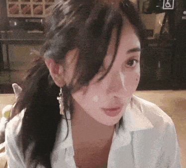 a woman wearing a white shirt and earrings looks at the camera with a handicap sign in the background