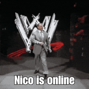 a man in a suit and tie is standing in front of a wrestling logo and says " nico is online "