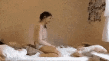a woman is sitting on a bed in a room with a dog .
