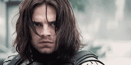 a close up of a man with long hair and a beard looking at the camera .