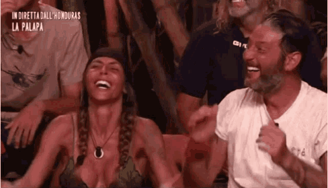a man and a woman are laughing in front of a crowd .