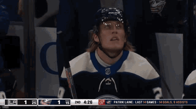 a hockey player wearing a bauer helmet sits in the dugout