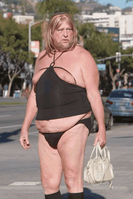 a man in a black top and panties is holding a purse