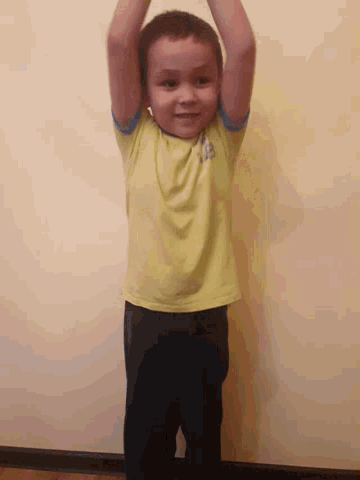 a young boy wearing a yellow shirt with the word la on it is hanging upside down