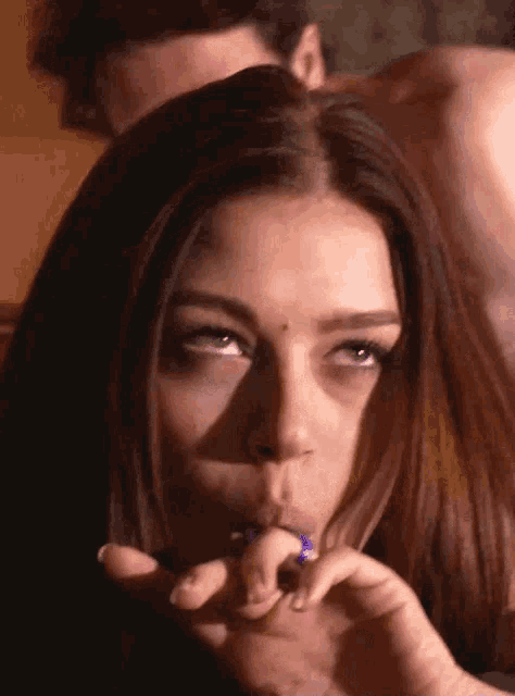 a woman smoking a cigarette with a purple ring in her mouth