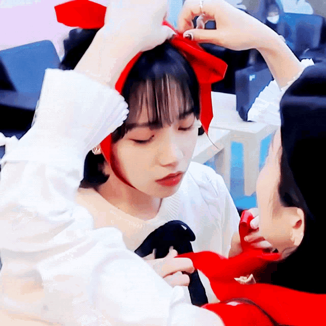 a woman wearing a red headband is being touched by another woman