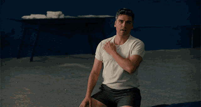 a man in a white shirt and black shorts is sitting on the ground