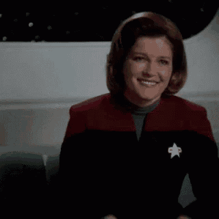 a woman in a star trek uniform is sitting on a couch looking down .